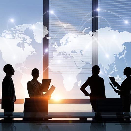 Team in silhouette in a meeting room, in front of a connected world map